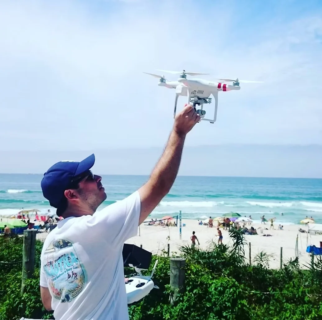 Aluno praticando pilotagem de drone próximo à praia no Rio de Janeiro